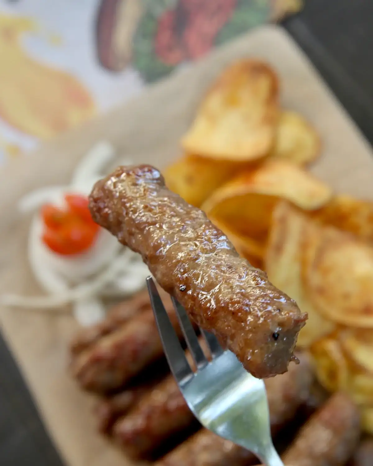 Ćevap na viljušci, izbliza, sa porcijom ćevapa i krompira u pozadini, Stara pivnica Zemun