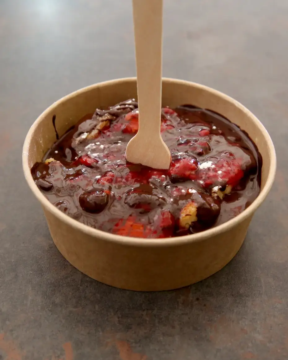 Kaiserschmarrn preliven čokoladom i malinama sa drvenom kašičicom