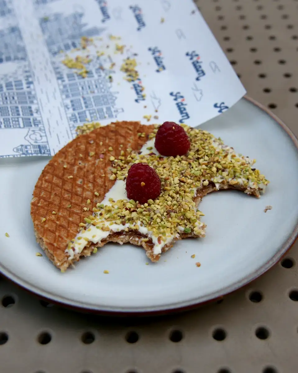 Zagrizen stroopwafel sa malinom, belom čokoladom i pistaćima na tanjiru, A'dam Stroopwafel Beograd